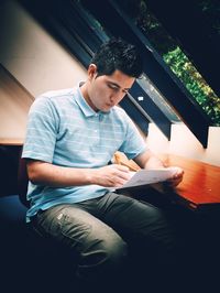 Young man sitting on mobile phone in city