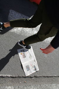 Low section of man walking over newspaper on road