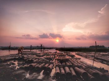 People on bamboo rafts over lake against sky during sunset