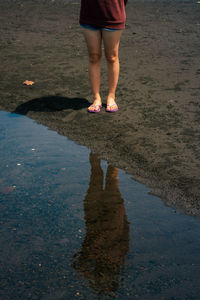 Low section of woman standing on puddle