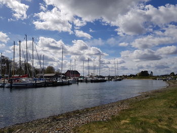 Sailboats moored at harbor against sky