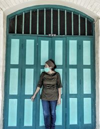 Full length of young woman standing against window