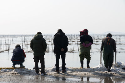 Rear view of people standing on snow covered landscape