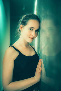 Portrait of young woman standing against wall