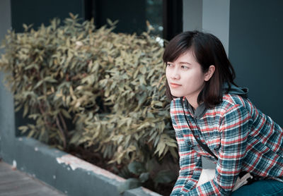 Thoughtful young woman looking away while sitting in city