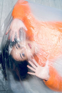Portrait of teenage girl wrapped in plastic on floor