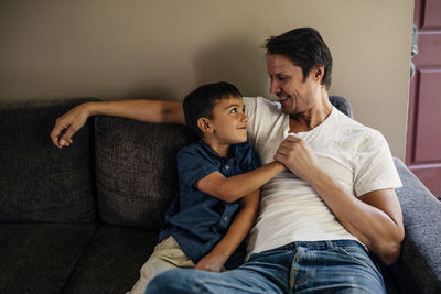 Happy father with son sitting on sofa at home