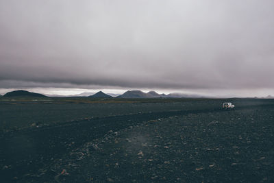 Car on landscape against cloudy sky