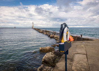 Life belt on groyne in sea against sky