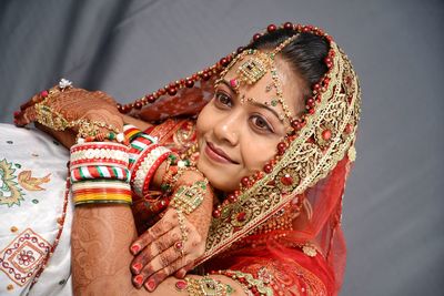 Close-up of beautiful young bride against curtain