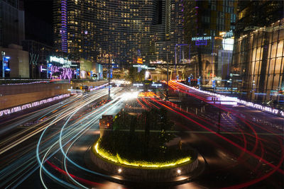 Light trails on city street by buildings at night