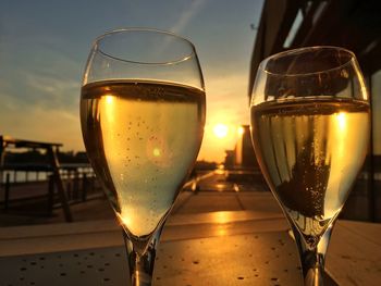 Close-up of beer glass on table against sky during sunset