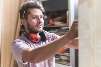 Male craftsperson with ear protectors working in workshop