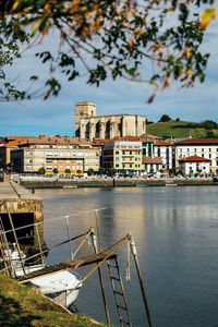 Buildings by river against sky