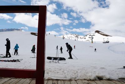 People skiing on snowcapped mountains against sky