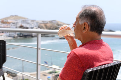 Side view of young man drinking water in city