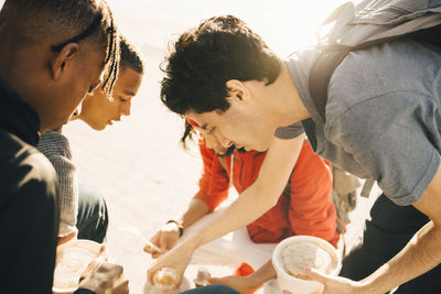 Friends eating take out food on promenade in city during sunny day