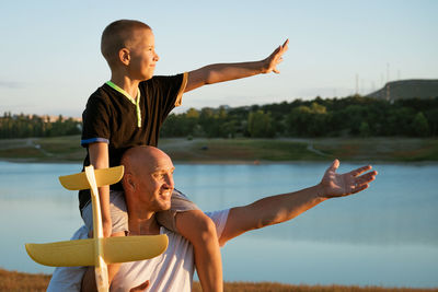 Side view of young man with arms raised standing at beach