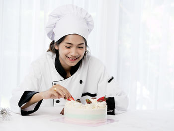 Chef decorating cake in plate on table