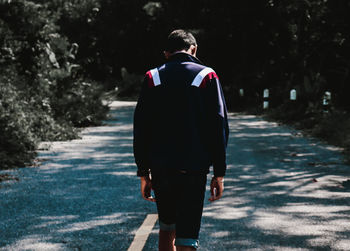 Rear view of man walking on footpath in city