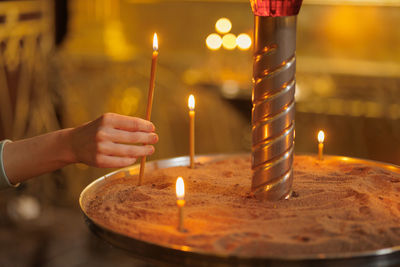 Close-up of hand holding lit candle