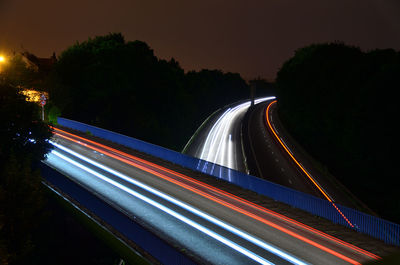 Light trails on road against sky at night