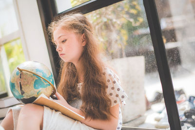 Portrait of a girl looking through window