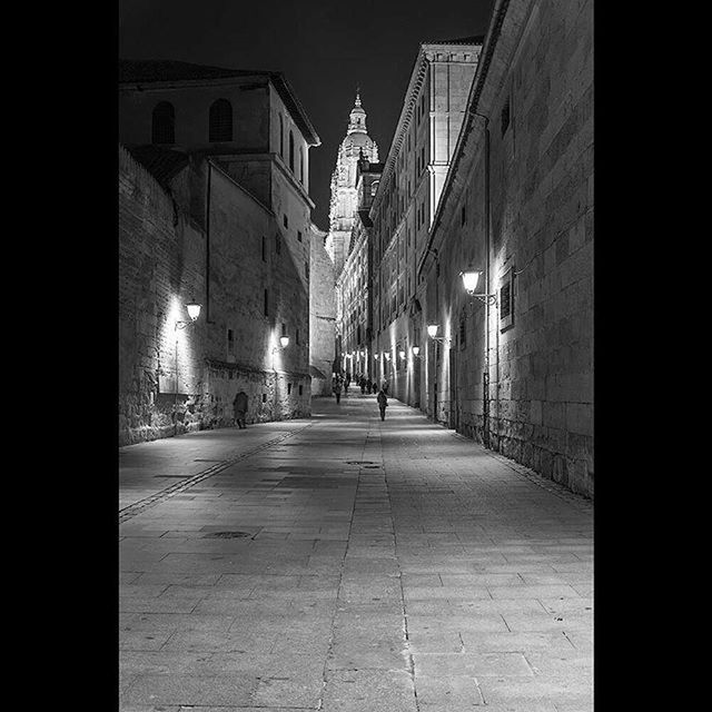 architecture, building exterior, built structure, the way forward, illuminated, street, night, city, diminishing perspective, building, cobblestone, street light, transportation, residential building, vanishing point, alley, lighting equipment, residential structure, narrow, road