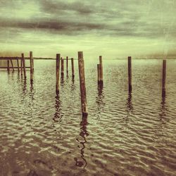 Pier on sea against cloudy sky