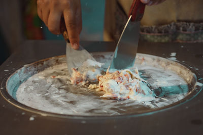 Midsection of person preparing food in cooking pan