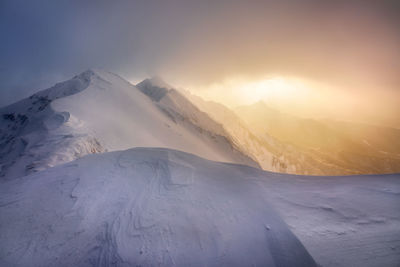 Scenic view of snowcapped mountains against sky during sunset