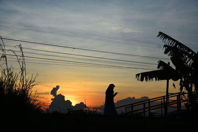 Silhouette people on bridge against sky during sunset
