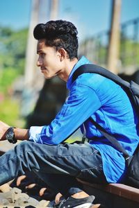 Side view of young man sitting on railroad track