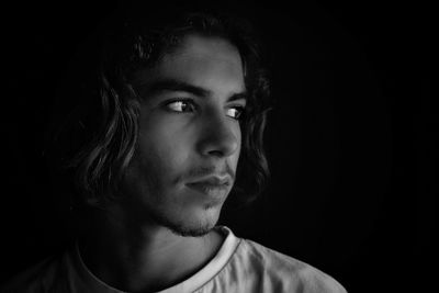 Close-up portrait of young man against black background