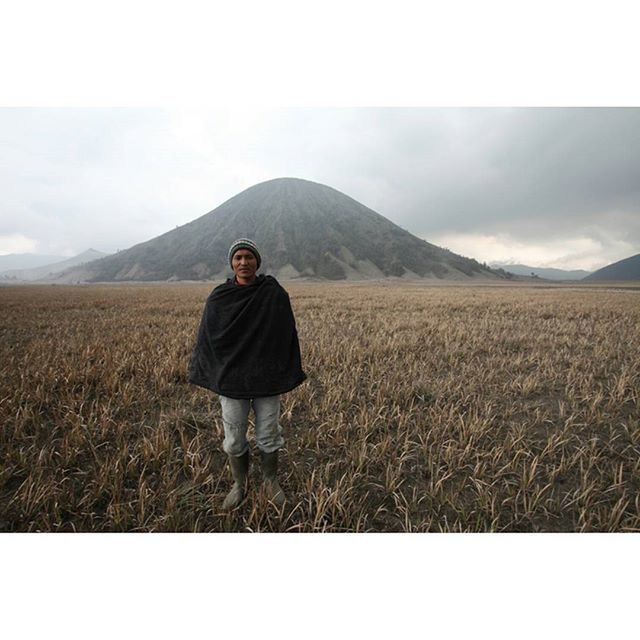 FULL LENGTH OF MAN STANDING ON FIELD AGAINST MOUNTAIN