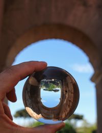 Close-up of hand holding glass against sky