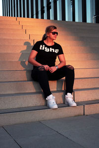 Full length of young woman sitting on staircase