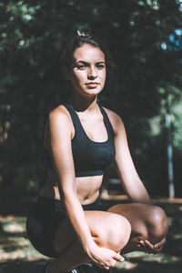 Portrait of teenage girl exercising against trees in park