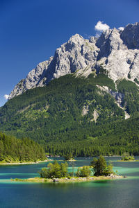 Scenic view of mountains and lake against clear blue sky