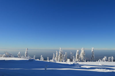 Snow covered landscape against blue sky