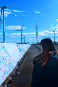 Rear view of woman standing on road against sky