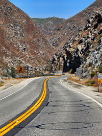 Empty road by mountain against clear sky