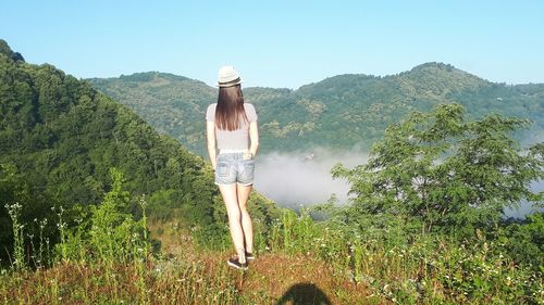 Rear view of woman looking at mountain against sky