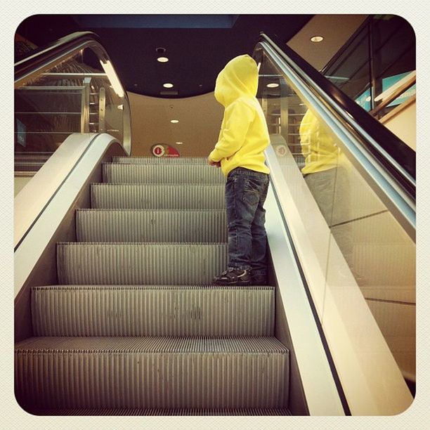 LOW ANGLE VIEW OF WOMAN STANDING ON ESCALATOR