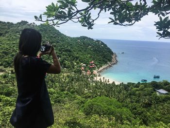 Rear view of woman photographing sea against sky