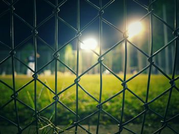 Illuminated baseball diamond seen through chainlink fence