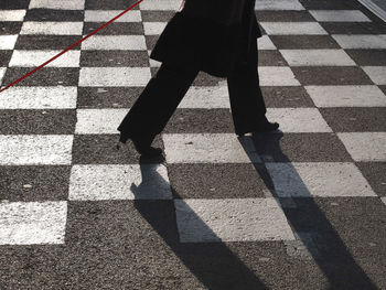 Low section of woman walking on checked patterned road