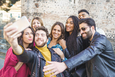 Young man taking selfie with cheerful friends in city