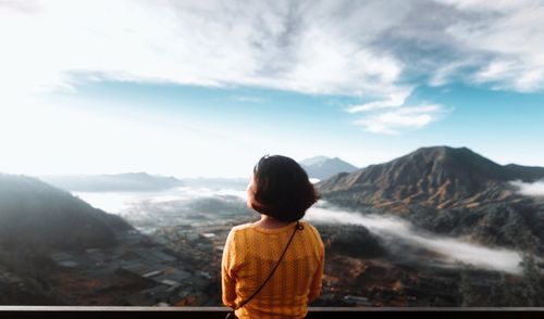 Rear view of man looking at mountains against sky