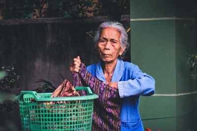 Portrait of woman sitting by laundry in basket